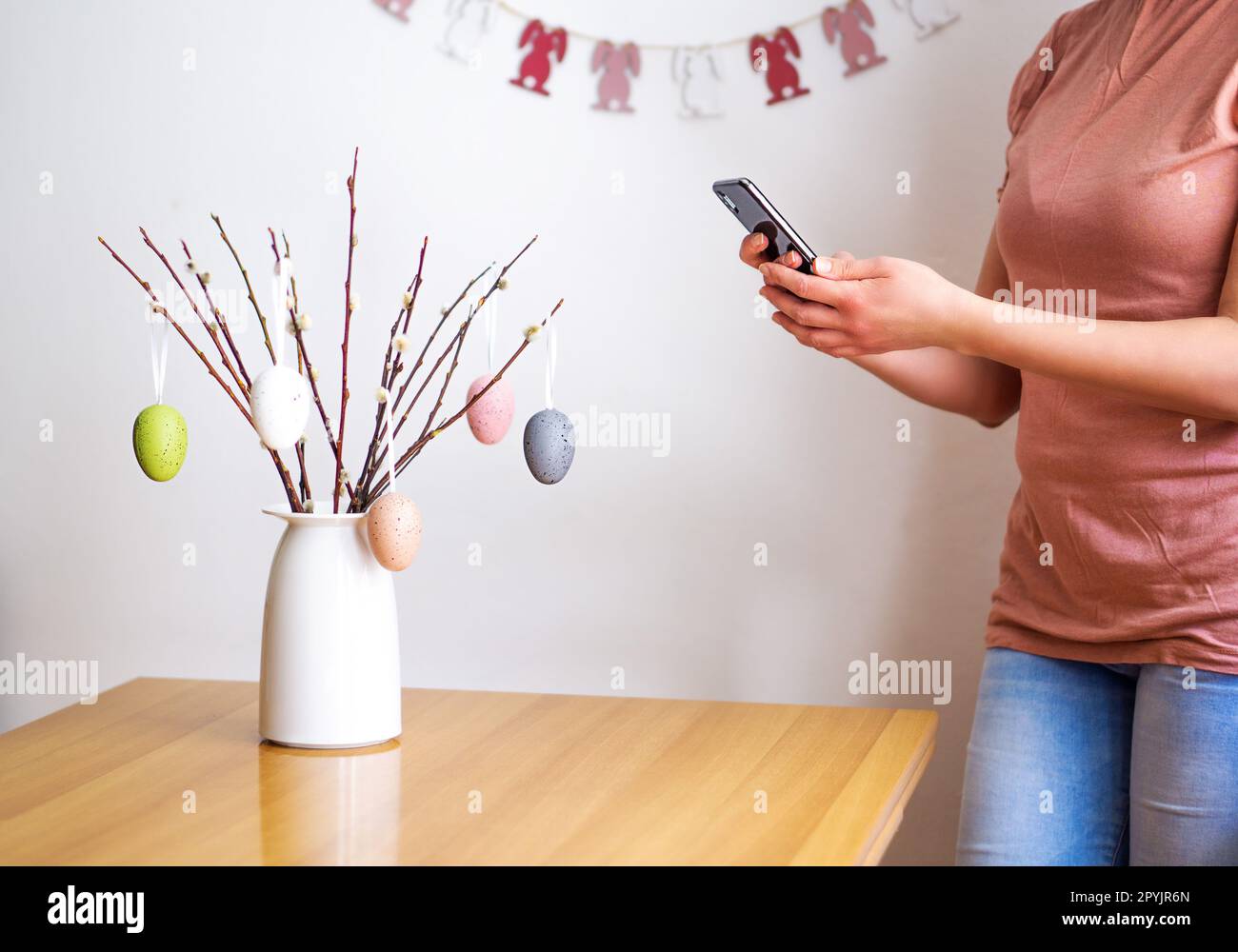 Female hands making a photo from a bouquet with willow branches and Easter eggs. Happy Easter. Stock Photo