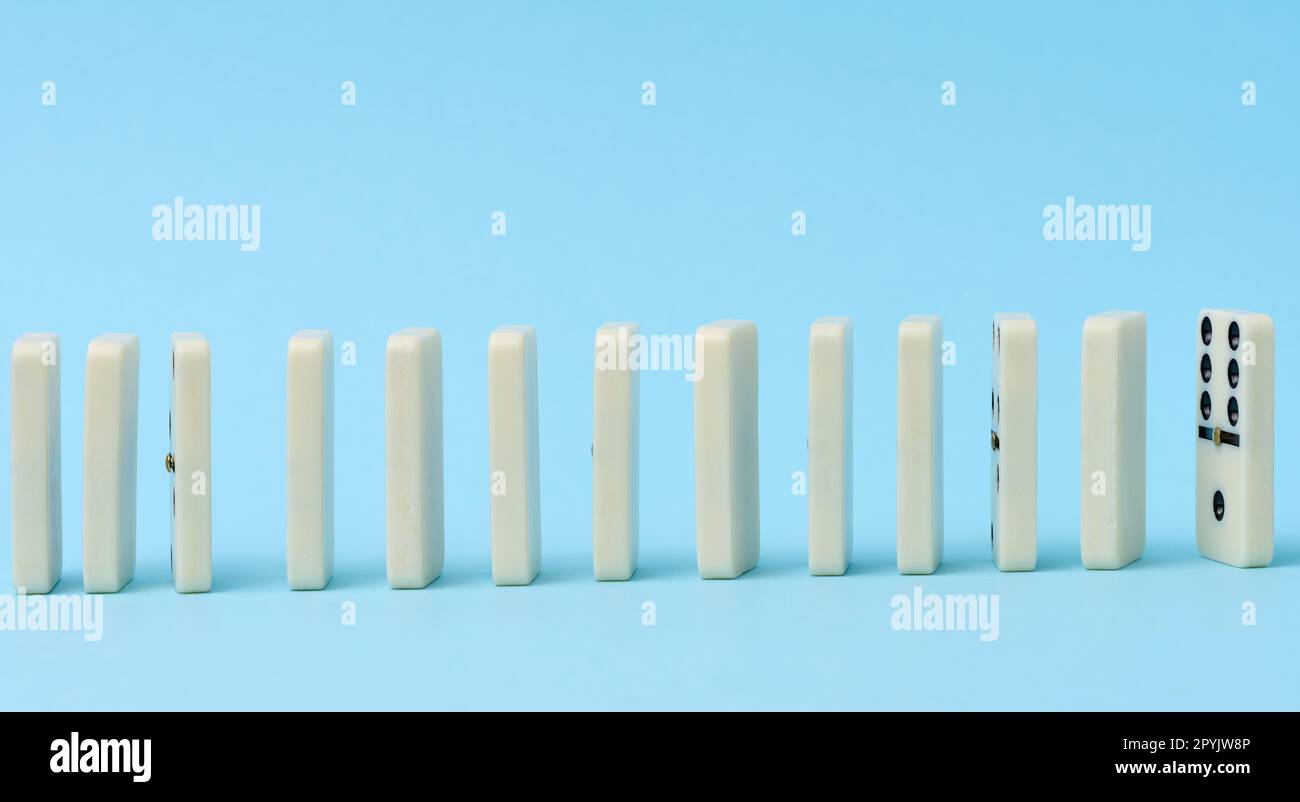 Dominoes standing in a row on a blue background, gambling Stock Photo