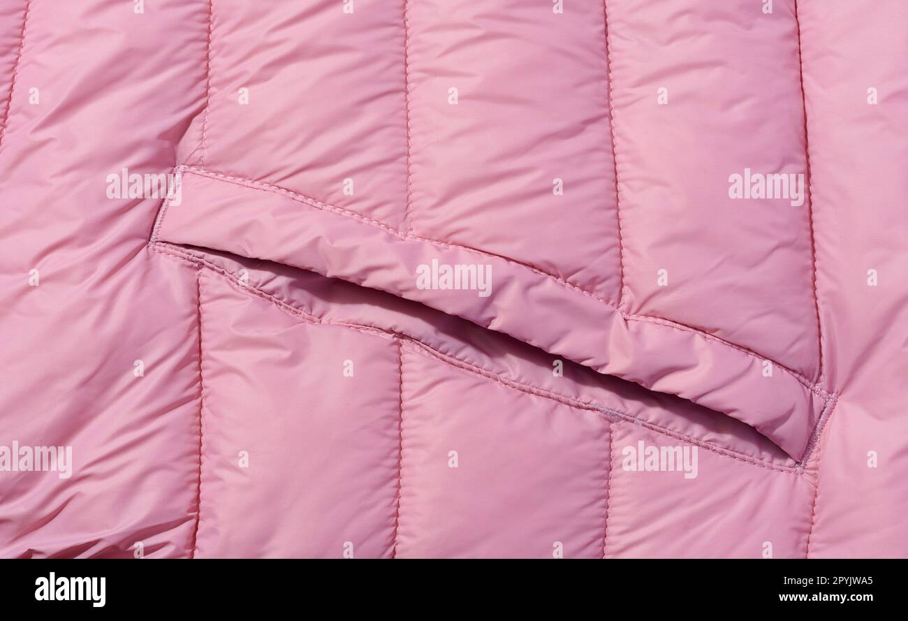 A fragment of pink fabric with down filling and stitching, fabric for jackets and coats Stock Photo