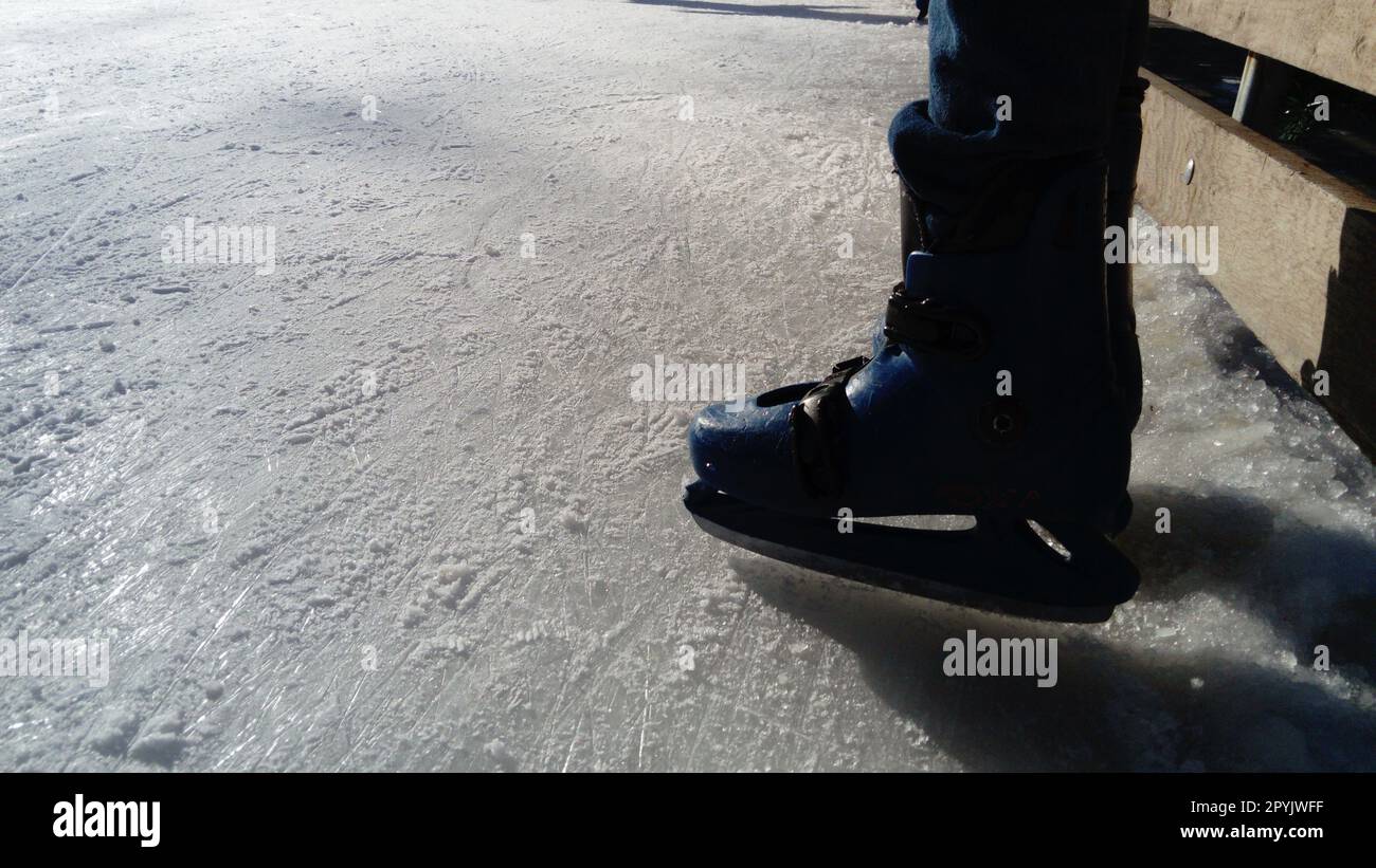 Feet with skates. Sports uniforms and equipment. Ice rink. Long shadows