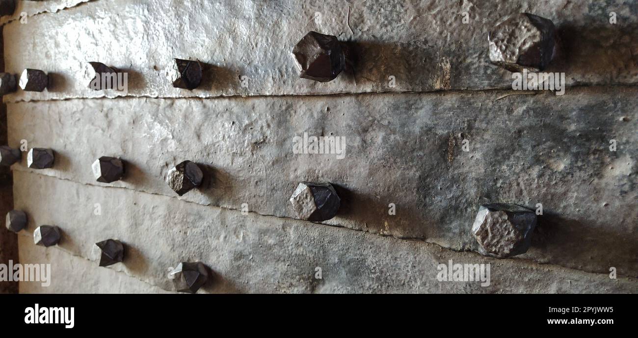 An old metal door with protruding rounded security features. Forged products. Kalemegdan Fortress, Belgrade, Serbia. Defensive fortifications of the Middle Ages Stock Photo