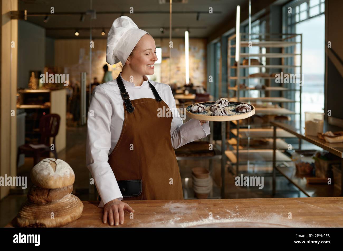 Pastry chef presenting freshly baked cookies standing at bakery kitchen Stock Photo