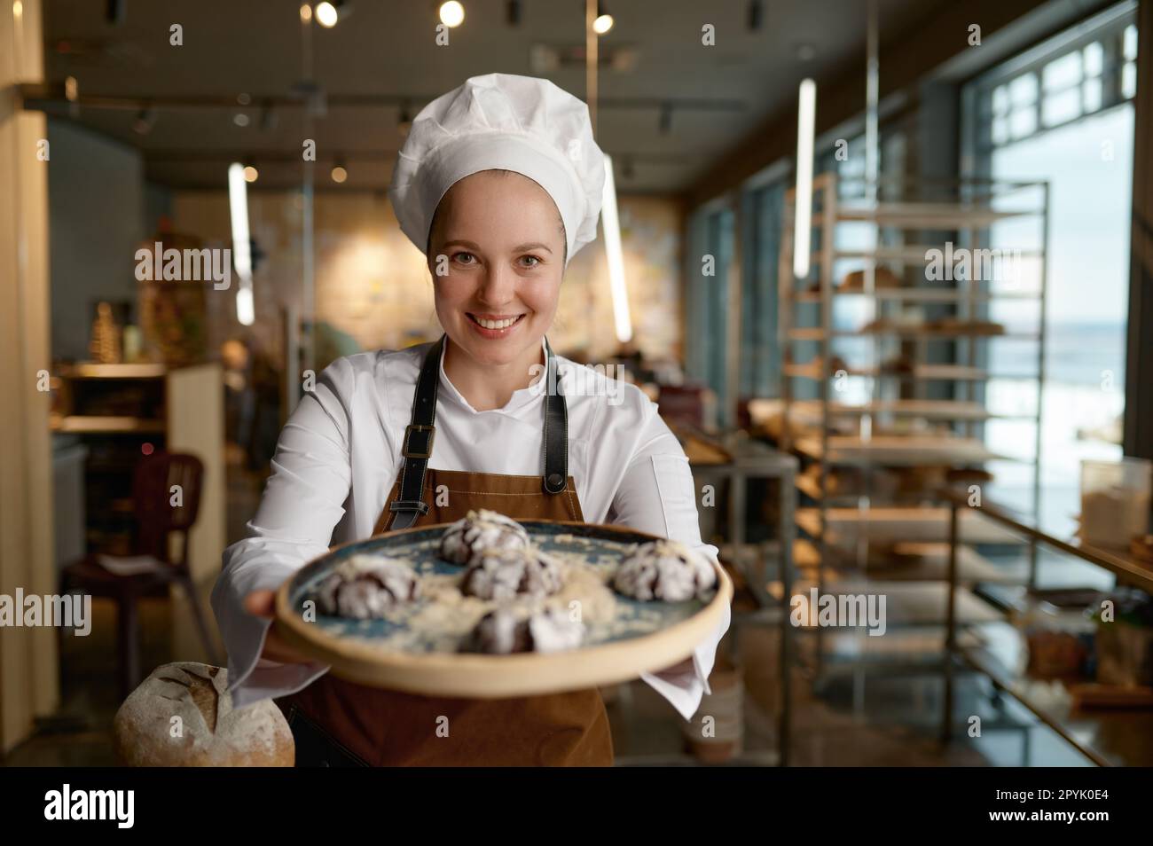 Pastry chef presenting freshly baked cookies at bakery kitchen Stock Photo
