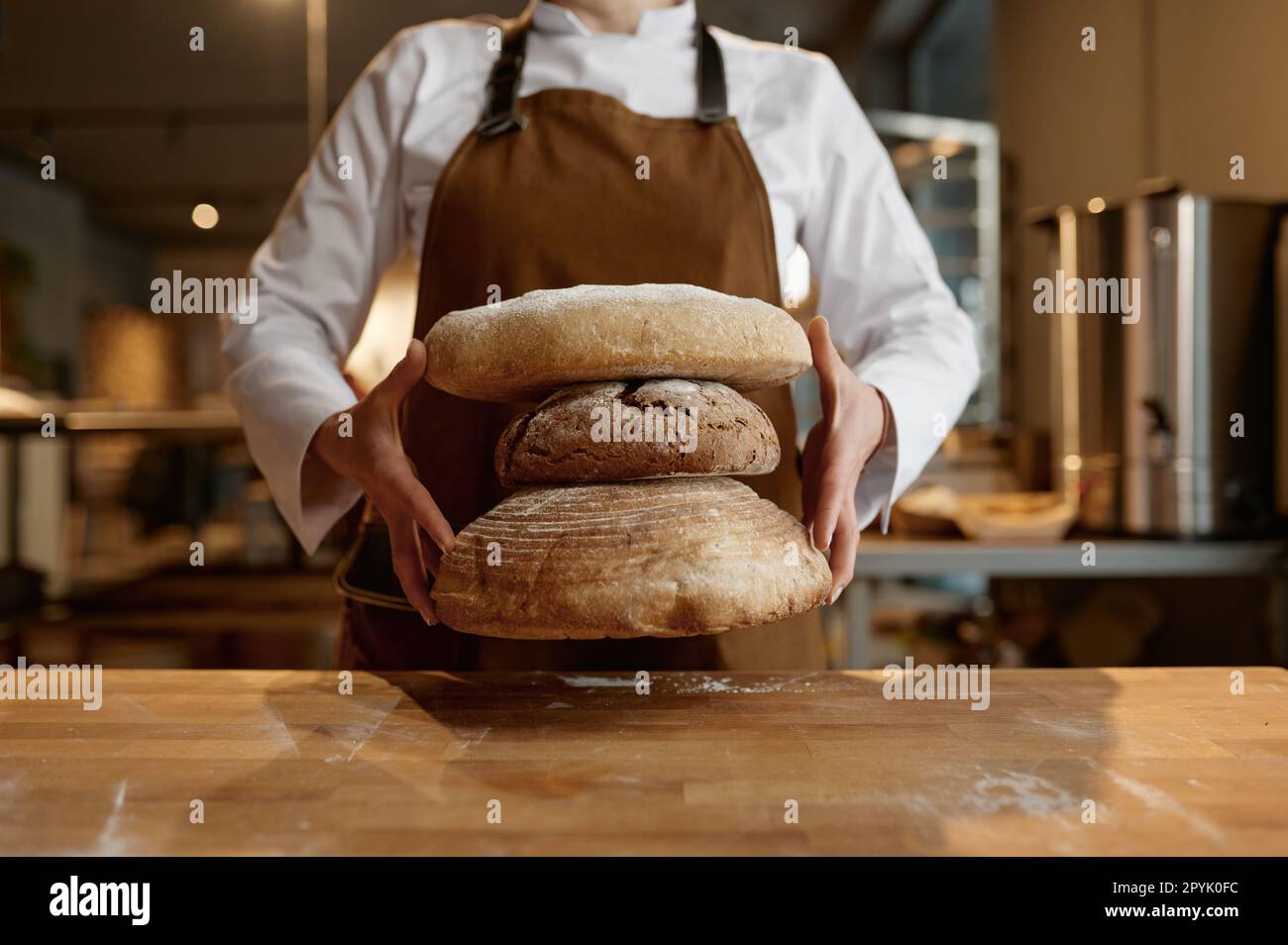 A baker holding stack of freshly baked bread Stock Photo