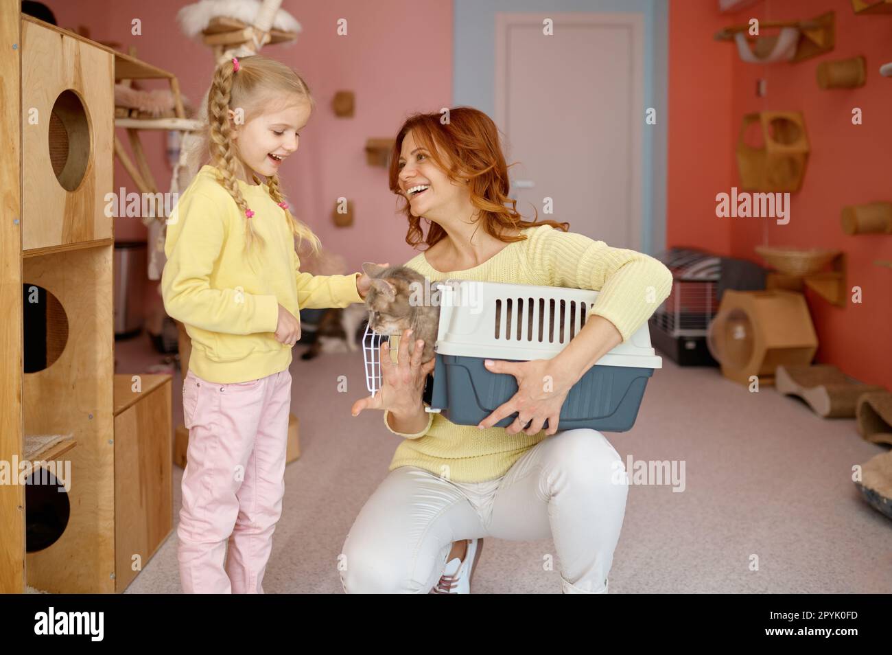 Happy parent and child choosing new pet in animal cat shelter Stock Photo