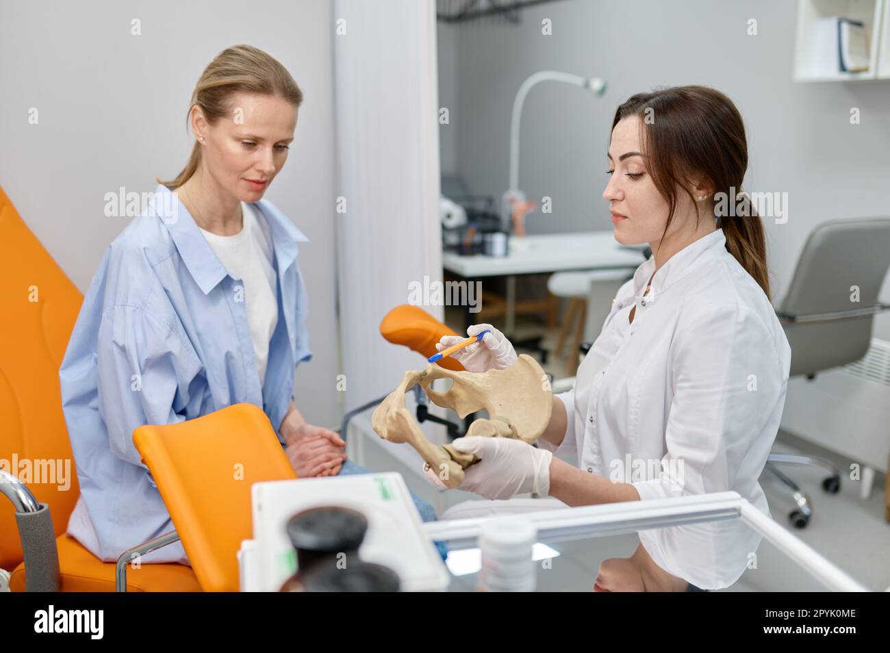 Gynecologist showing bones of female pelvis and giving consultation to woman Stock Photo