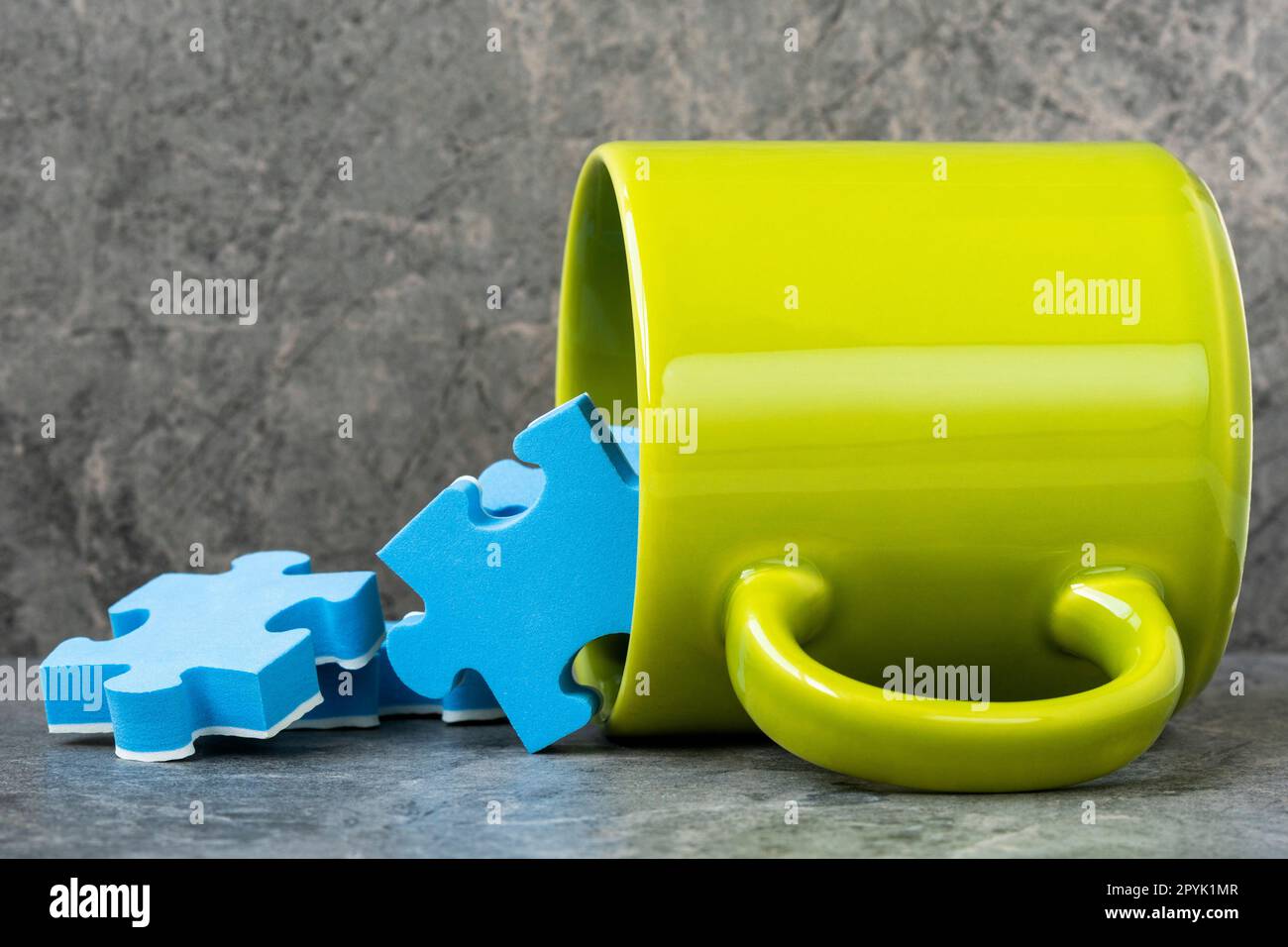 Green cup of coffee and scattered blue puzzle pieces Stock Photo