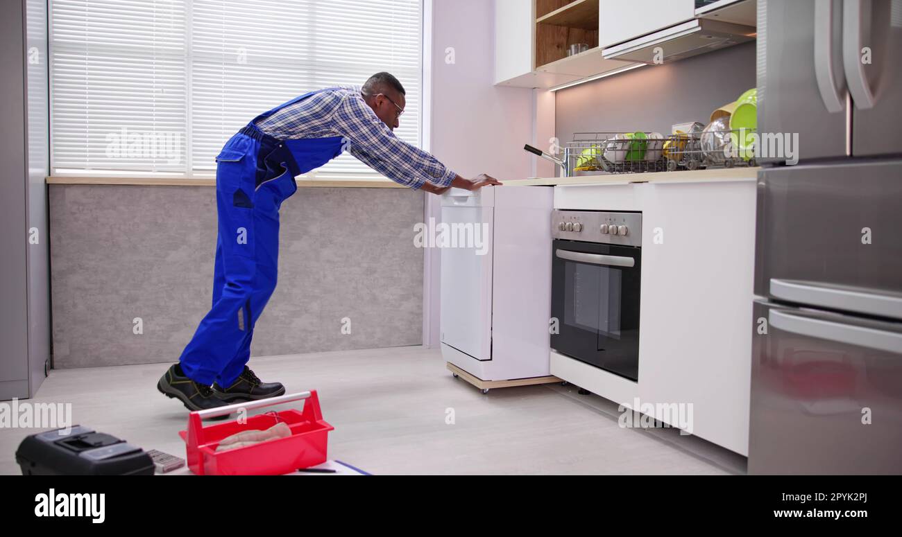 Male Mover In Uniform Placing Dishwasher Stock Photo - Alamy