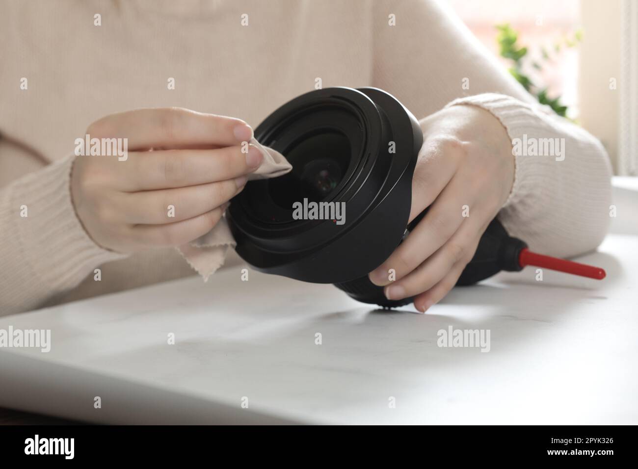 female photographer cleaning dslr fisheye camera lens with microfiber