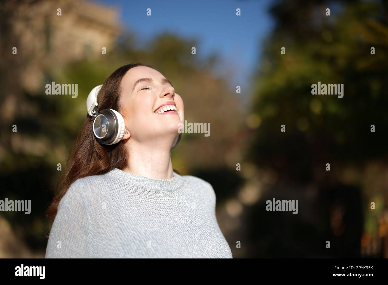 Happy woman breathing fresh air and laughing listening audio Stock Photo