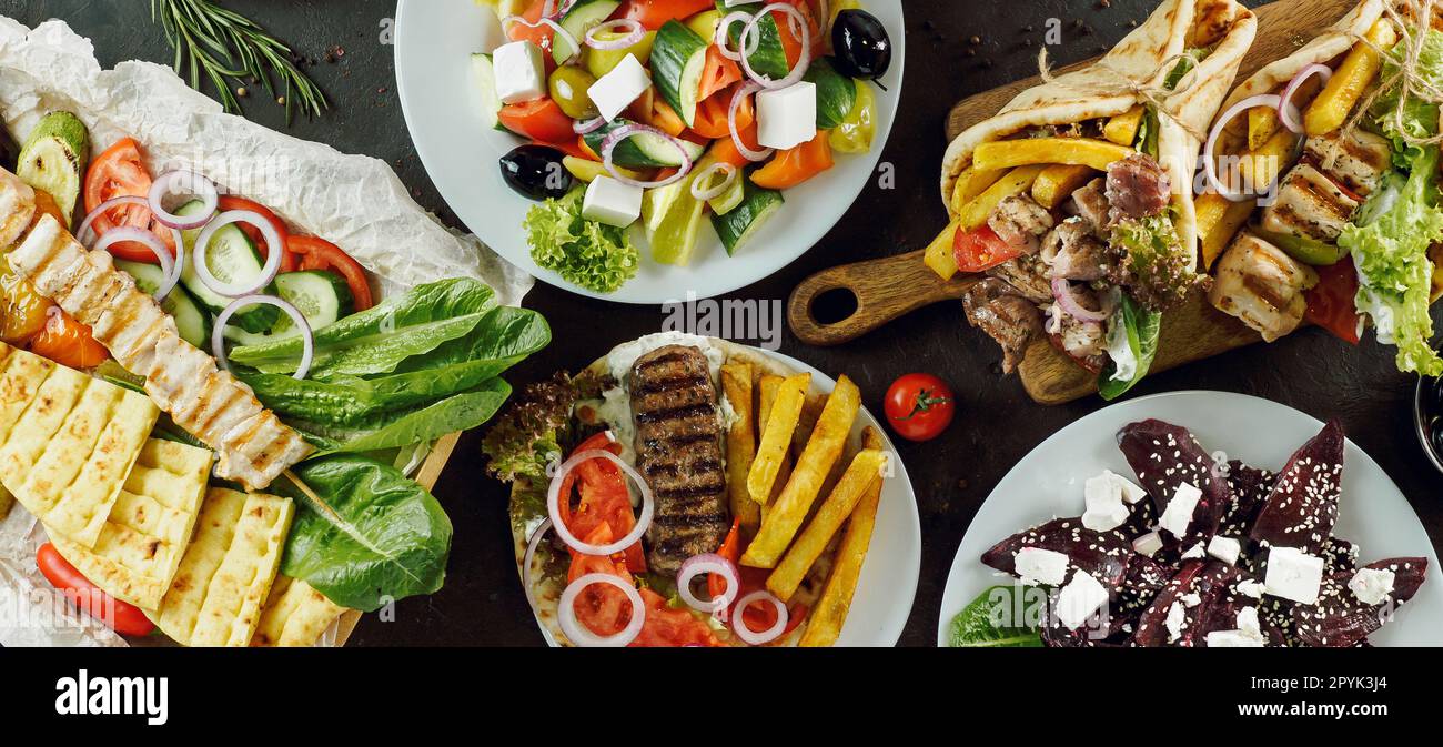 Greek food assorted on dark background, long horizontal banner. Gyros