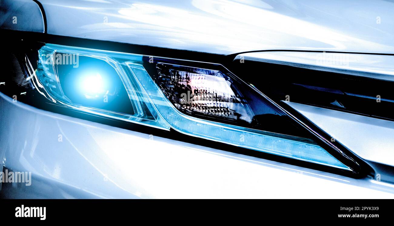 Closeup headlamp light of a white luxury car. Automotive industry concept. Electric car or hybrid vehicle concept. Automobile leasing and insurance concept. Auto leasing business. Electric vehicle. Stock Photo