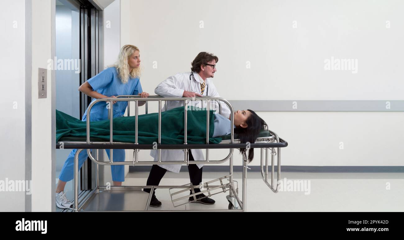 Nurse and paramedic pushing the patient bed out of the elevator to the emergency room of the hospital. Stock Photo