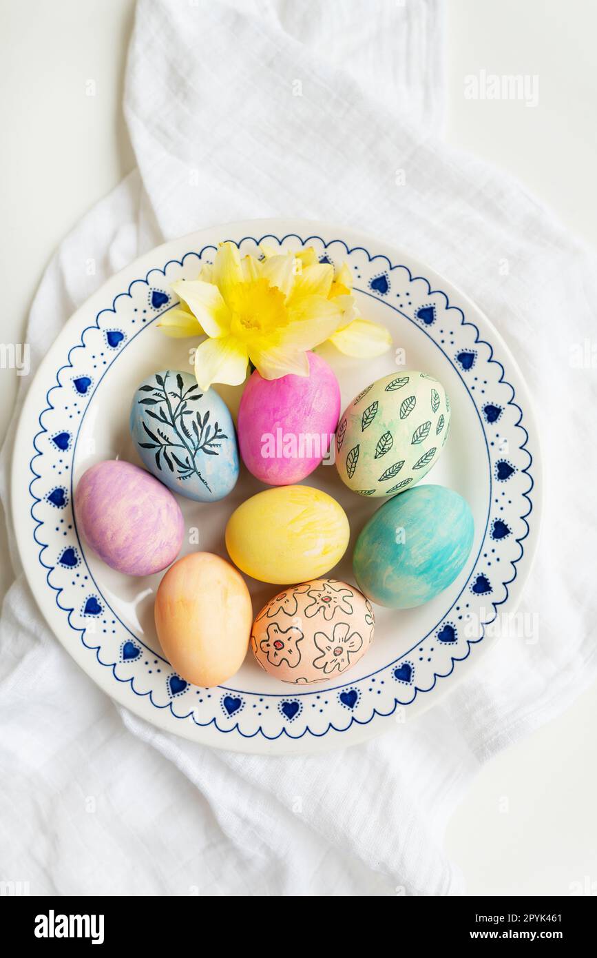 Easter eggs are painted in different colors and patterns on the plate. Top view, Easter celebration concept. Stock Photo