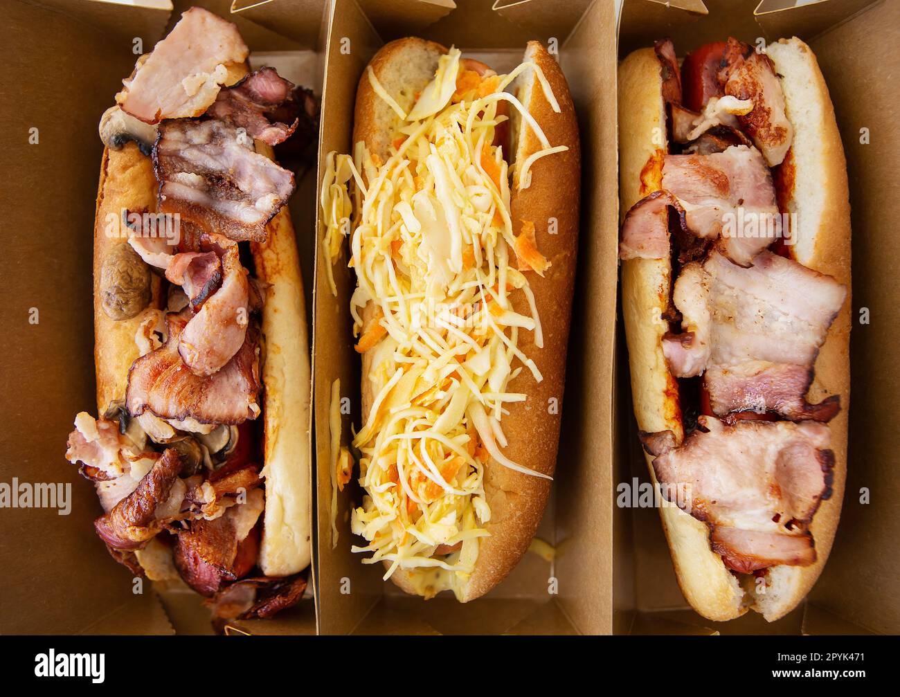 American hot dog with different flavors, with cheese and crispy onions on a white table in a minimalist style. Fast food, takeaway food, food for motorists. Hot dog sandwich with sausage. Stock Photo