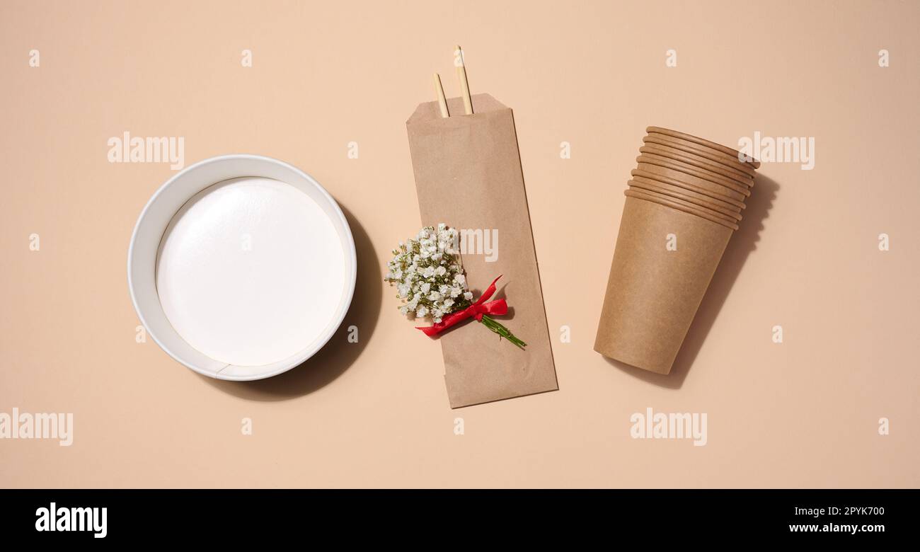 Empty paper plate for soup and brown cardboard cups on beige background