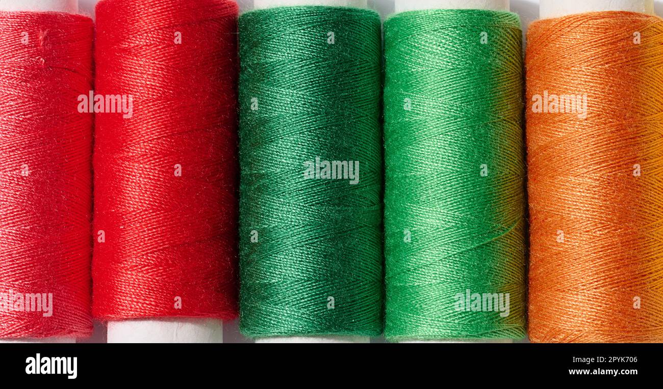 Multicolored spools of sewing threads on a white background, top view Stock Photo