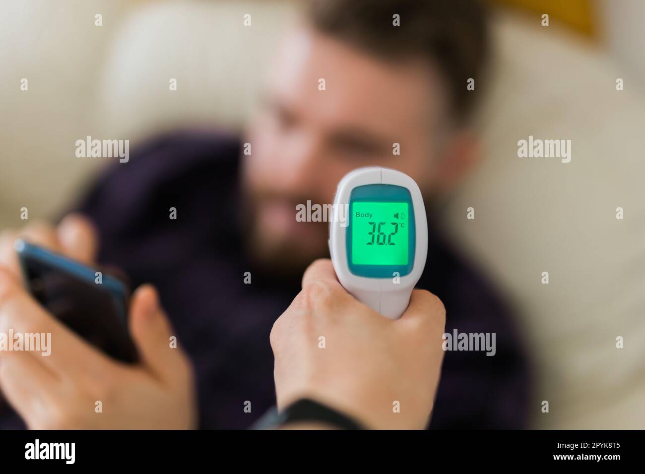 Close up of infrared digital forehead thermometer in hand,fever examination and measures to prevent and screen people check body temperature during its reopening after COVID-19 Coronavirus Lockdown, New normal Stock Photo