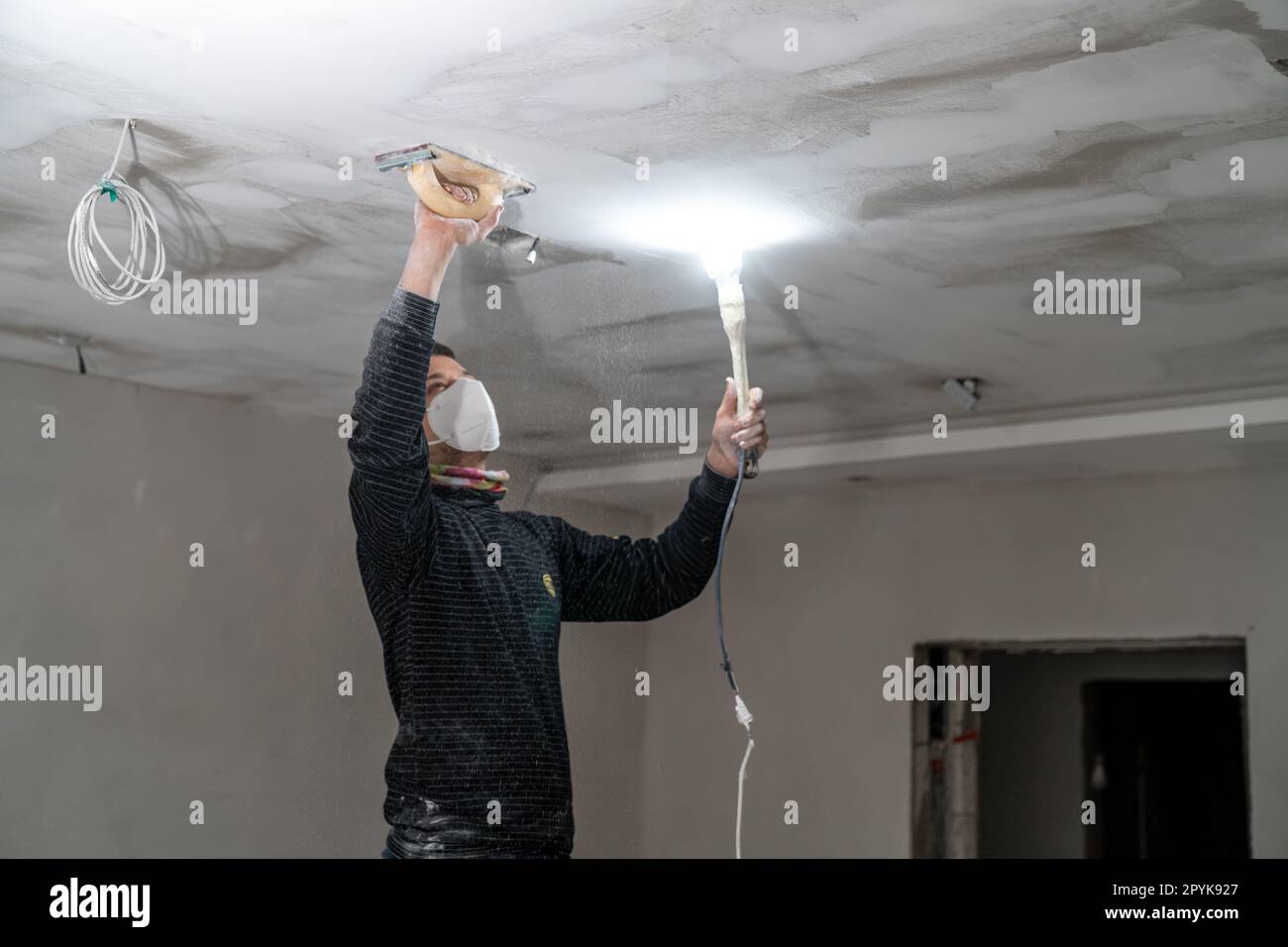 sanding a plasterboard ceiling in a new building with a trowel Stock Photo