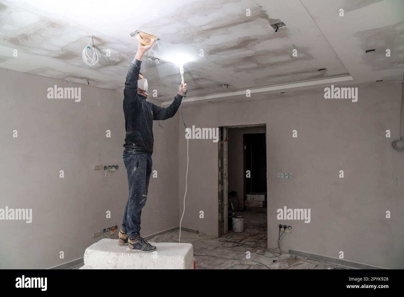 sanding a plasterboard ceiling in a new building with a trowel Stock