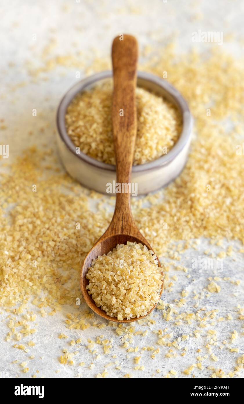 Wooden scoop and bowl with Dry uncooked bulgur wheat grain close up. Healthy food Stock Photo