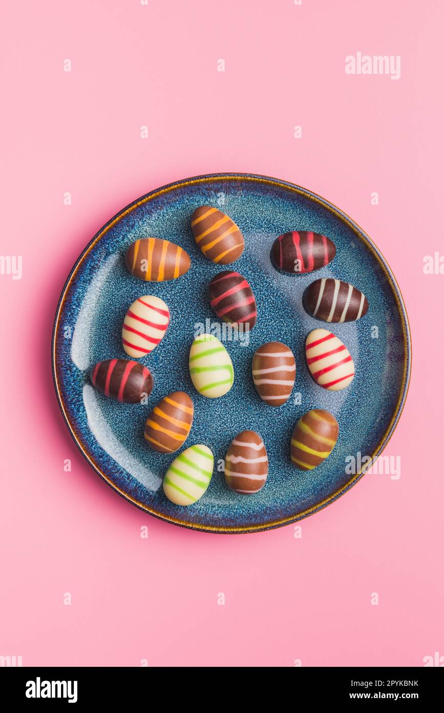 Chocolate easter eggs on plate on pink background. Top view. Stock Photo