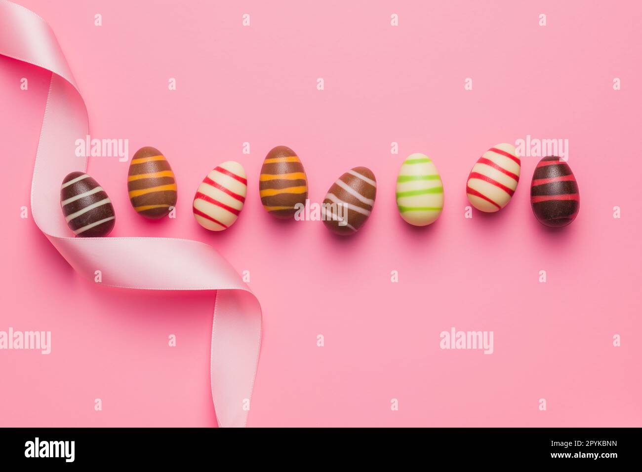 Chocolate easter eggs on pink background. Top view. Stock Photo