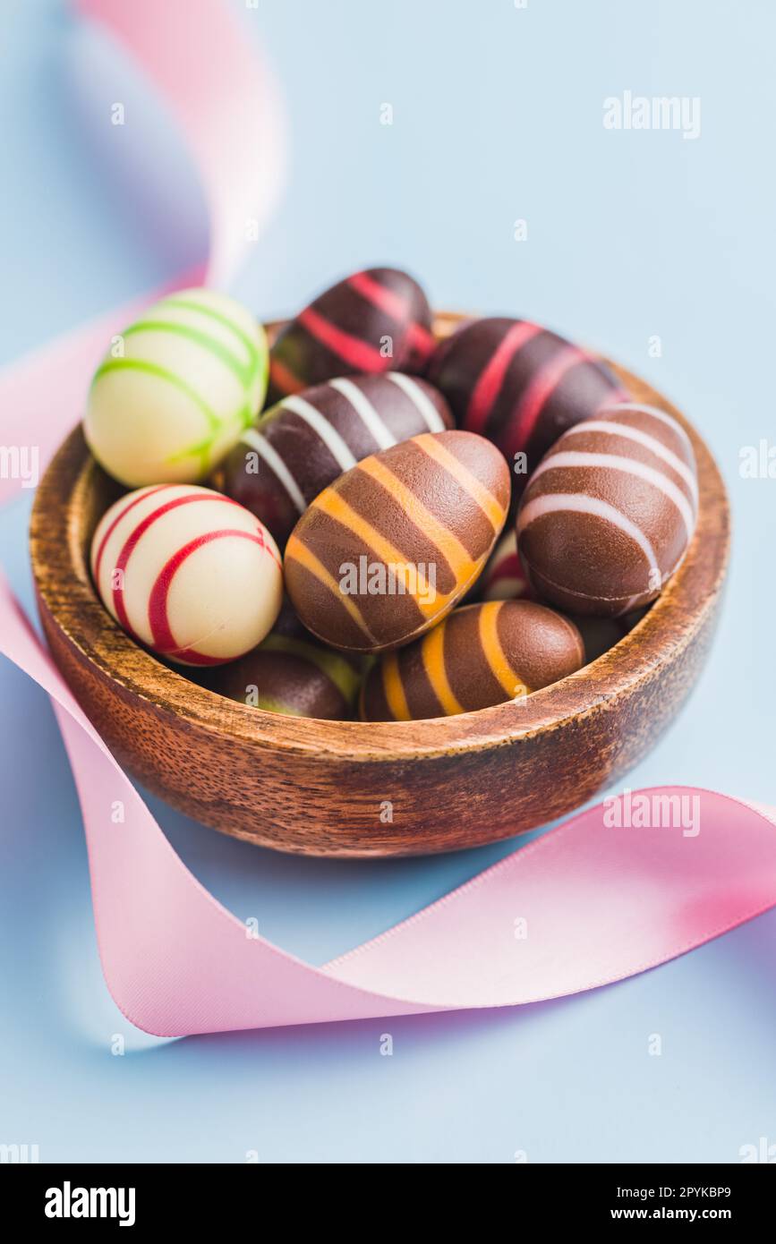 Chocolate easter eggs in bowl on blue background. Stock Photo