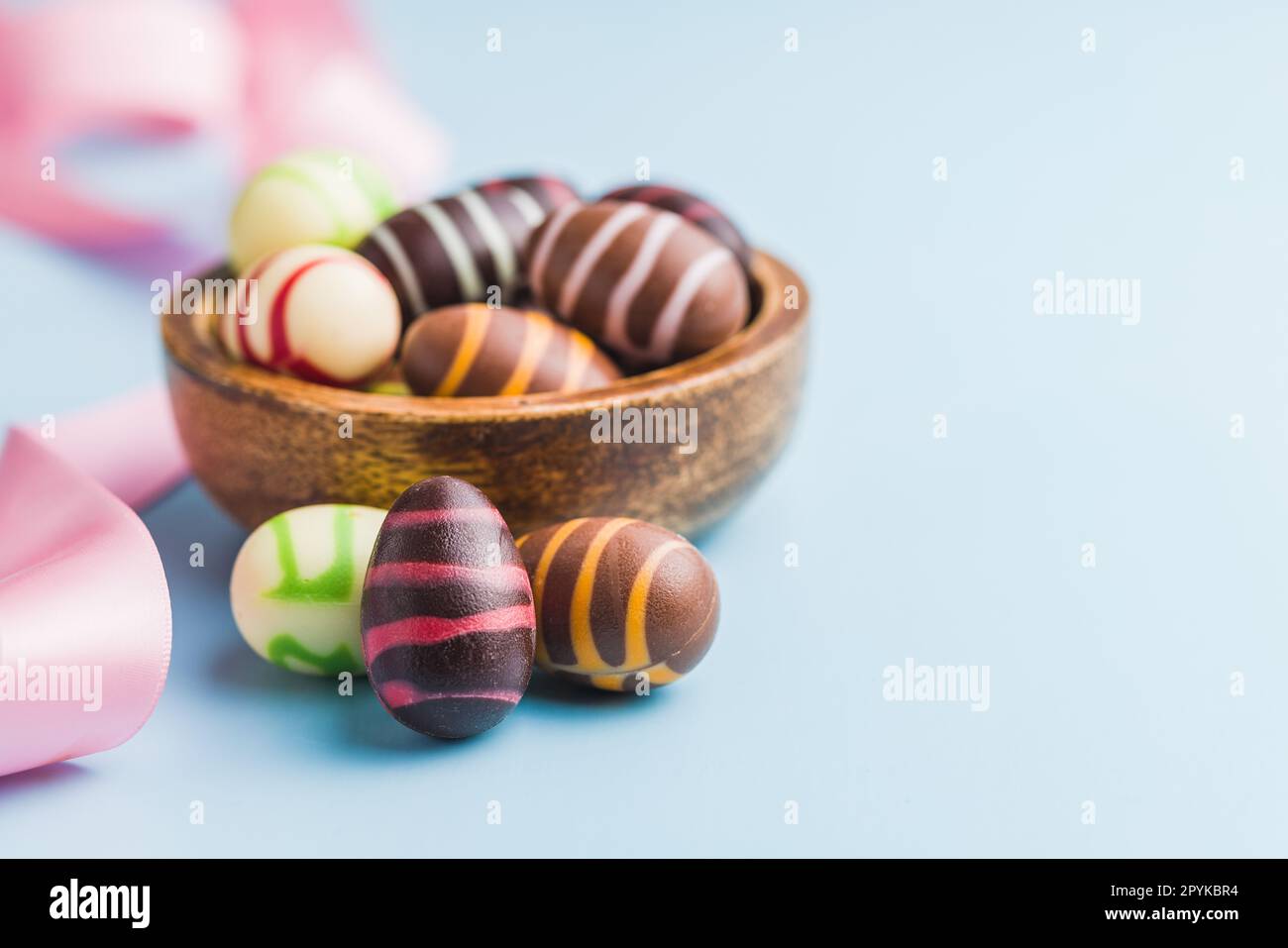 Chocolate easter eggs in bowl on blue background. Stock Photo
