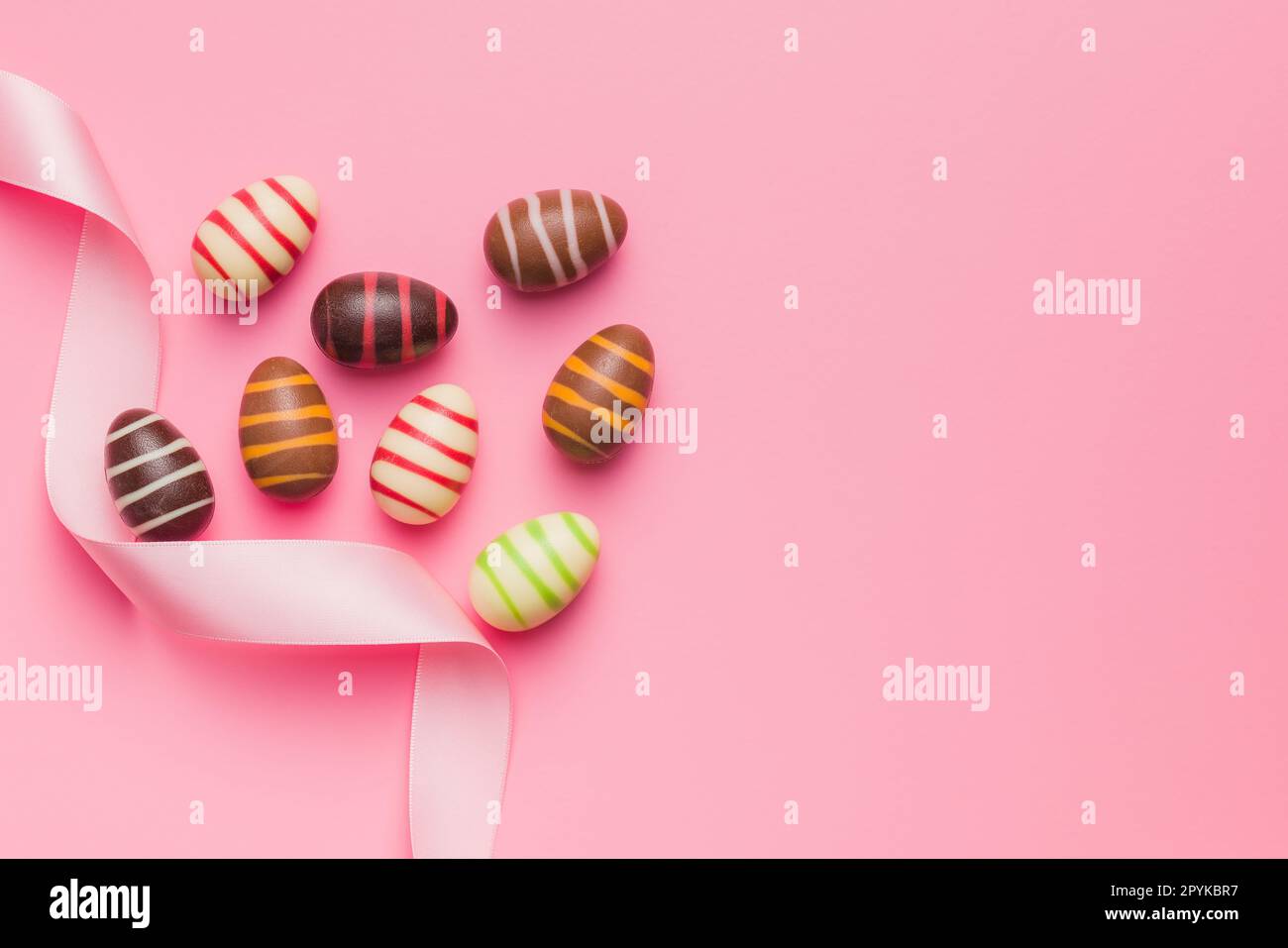 Chocolate easter eggs on pink background. Top view. Stock Photo