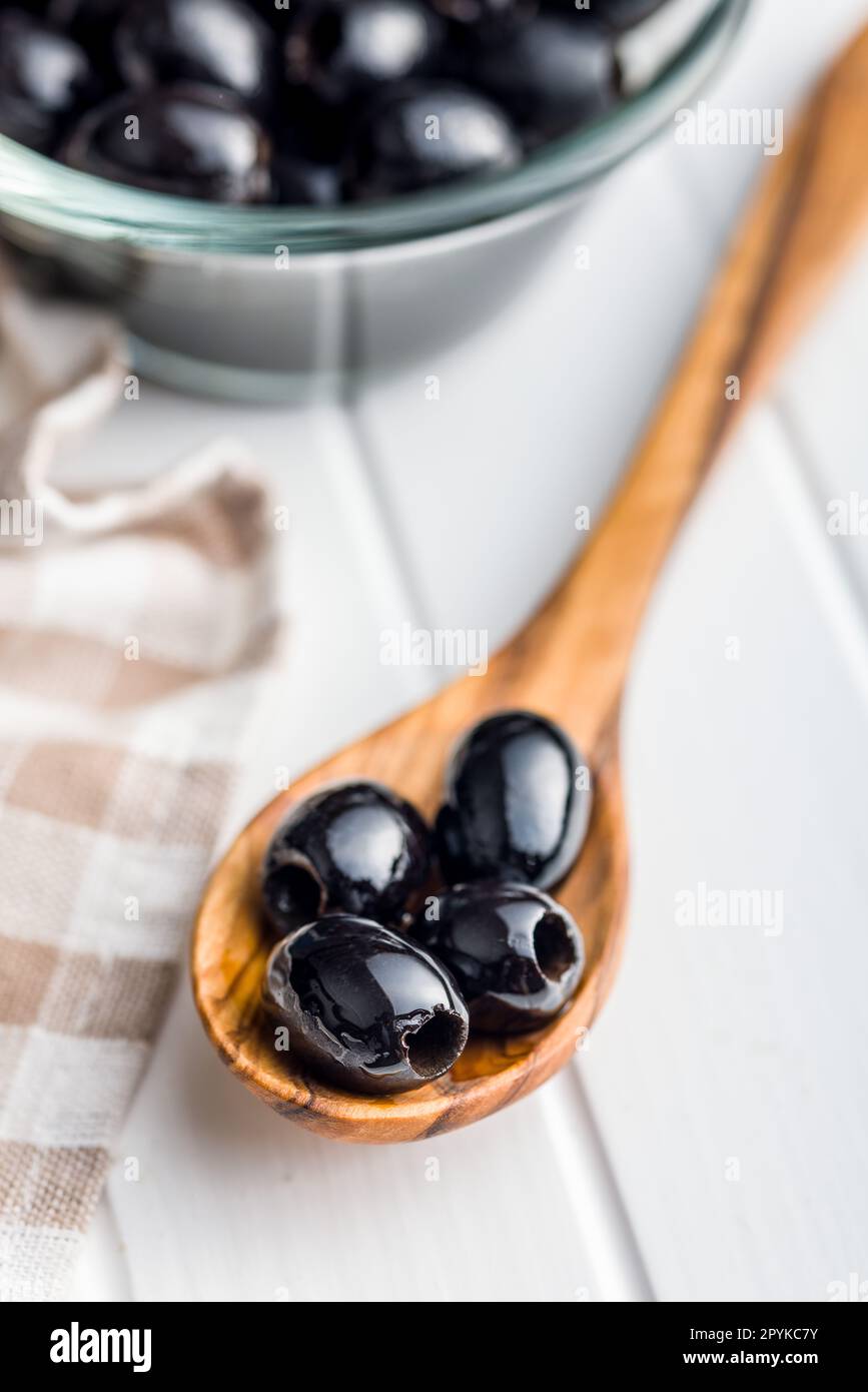 Pitted black olives in wooden spoon. Stock Photo