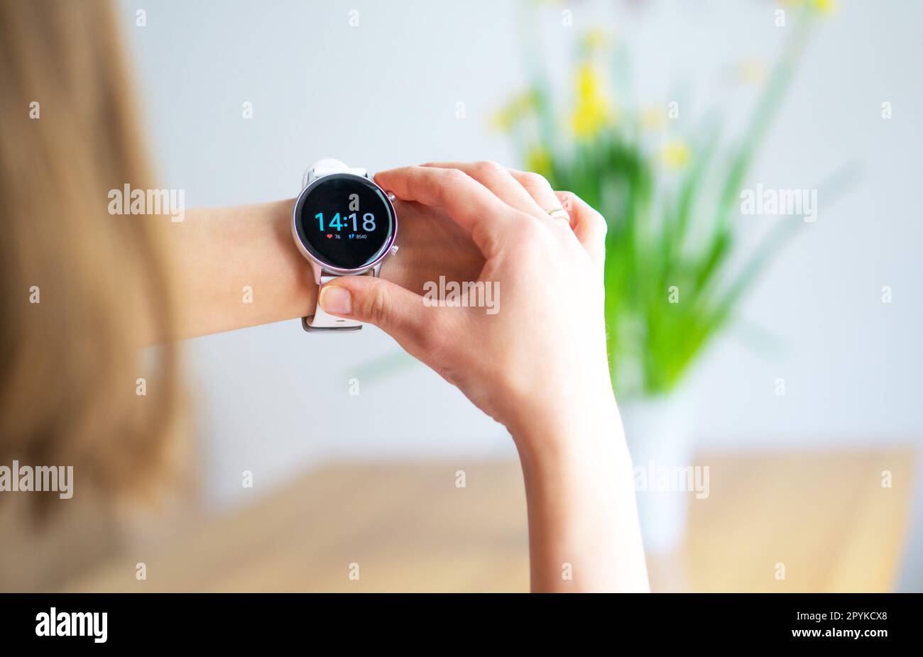 Hand of woman wearing smart watch on Easter background. Technology and people concept. Stock Photo