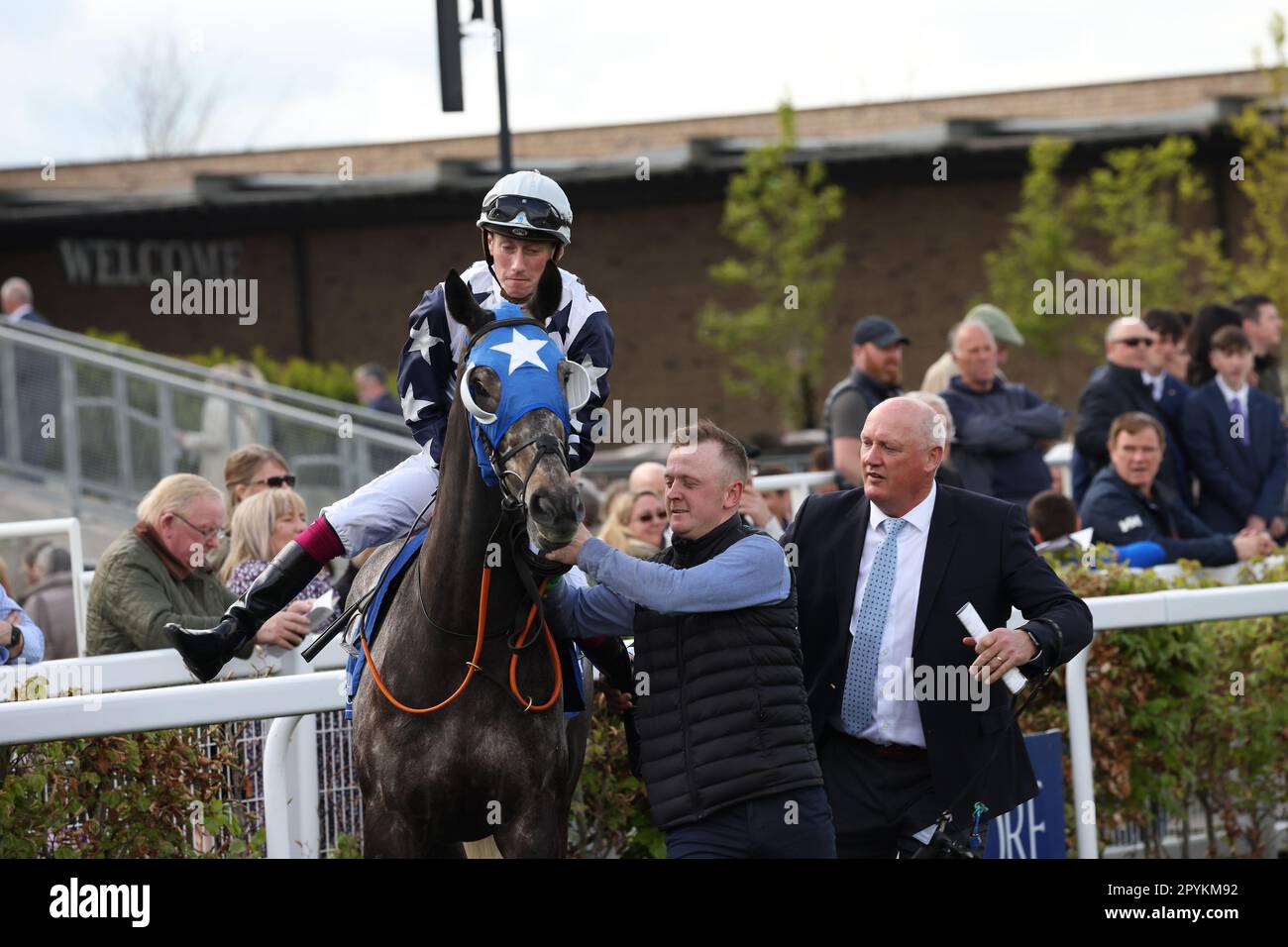 Trainer, Willie McCreery, extreme right helps Nathan Crosse, Jockey