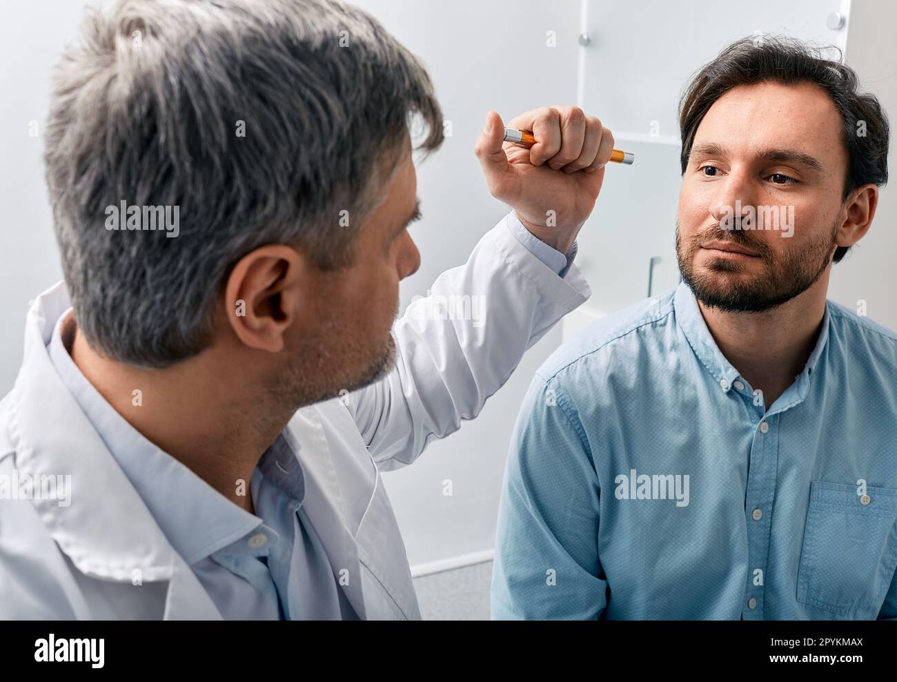 Neurologist doctor examining male patient, checking basic reflexes of human by shining flashlight into his eyes. Neurologist's consultation, neurology Stock Photo