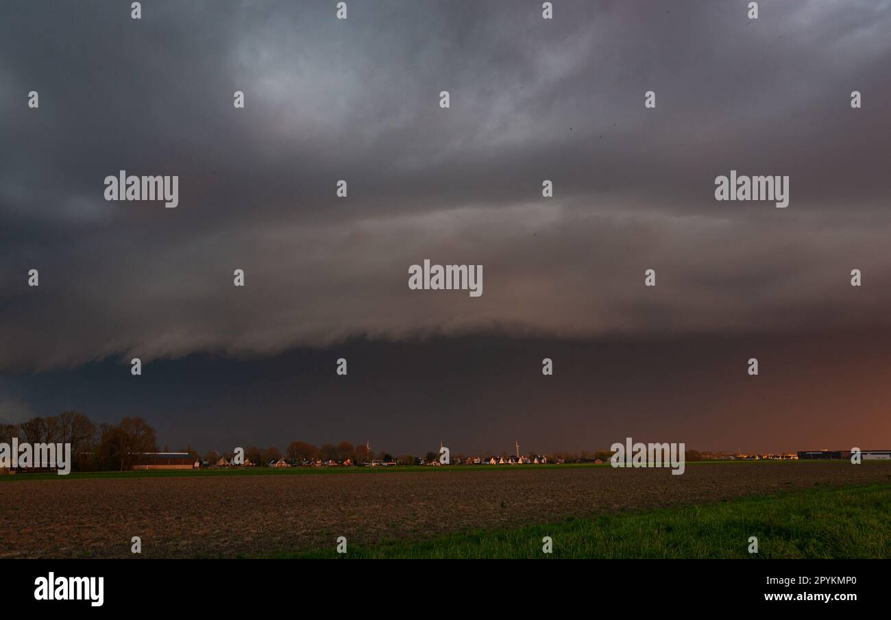 A shelf cloud of a severe thunderstorm rolls over the plains at sunset Stock Photo