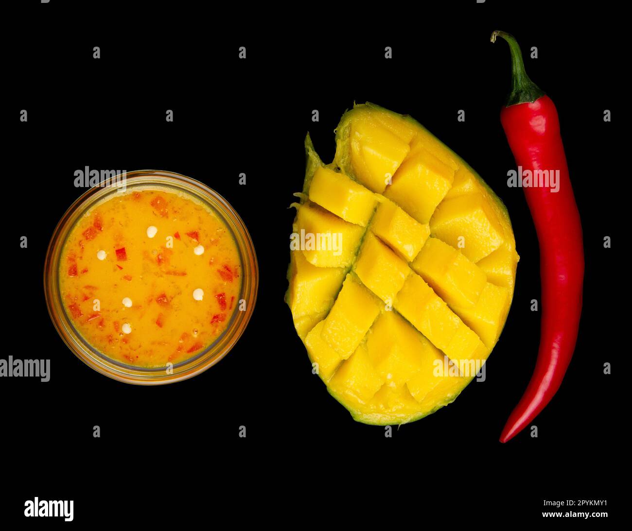Top view of sweet mango chili sauce, diced half of mango and whole red hot pepper on black background Stock Photo