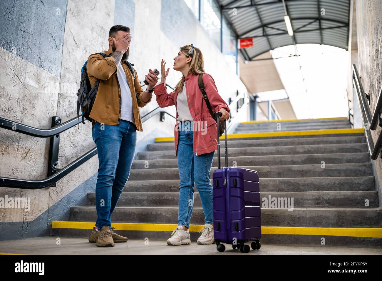 Adult couple missed the departure of the train. The are arguing at at the train station. Stock Photo