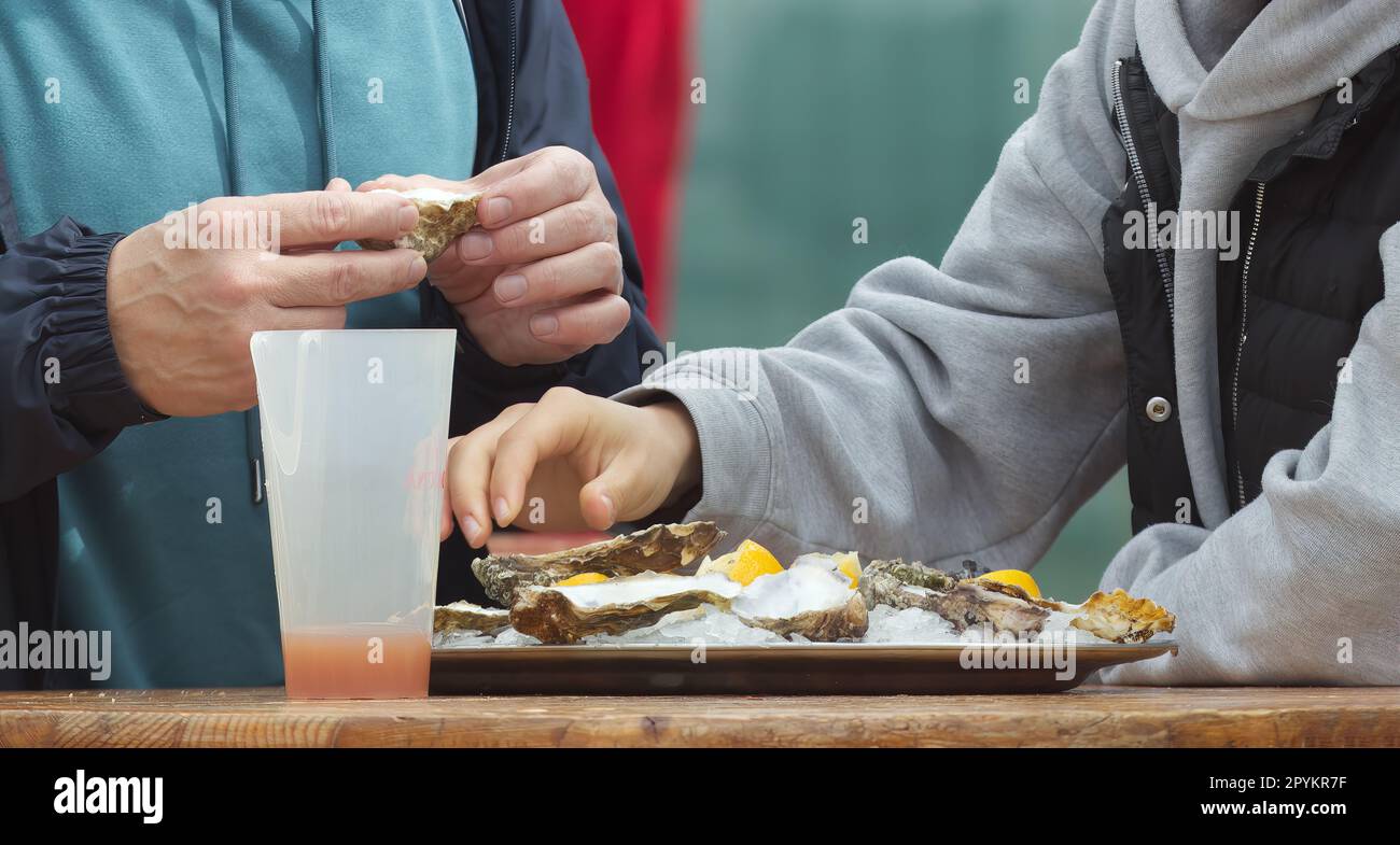 Eating oysters at a street food market, womens hands holding an oyster