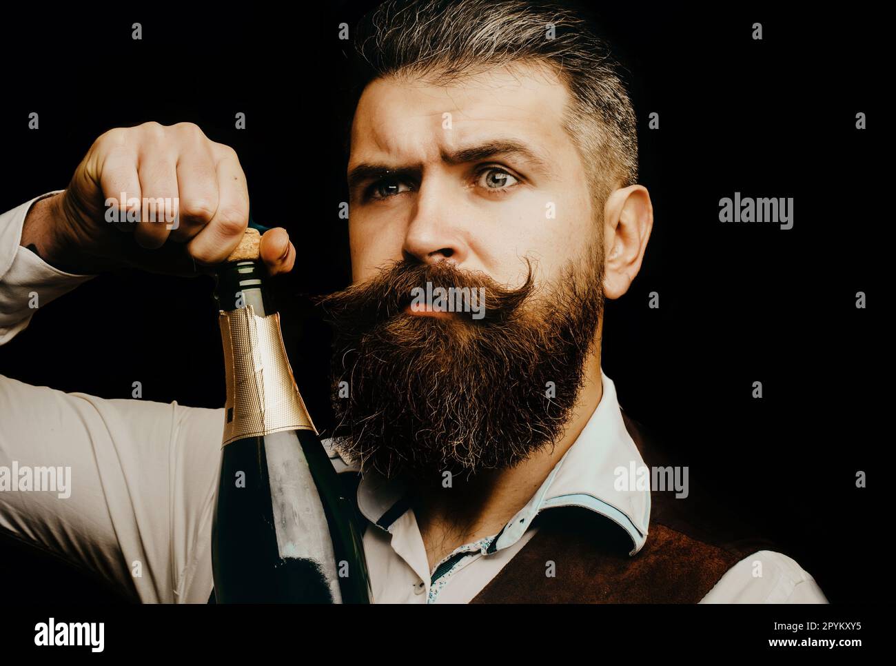Portrait of a bearded waiter holding a champagne bottle. Close up