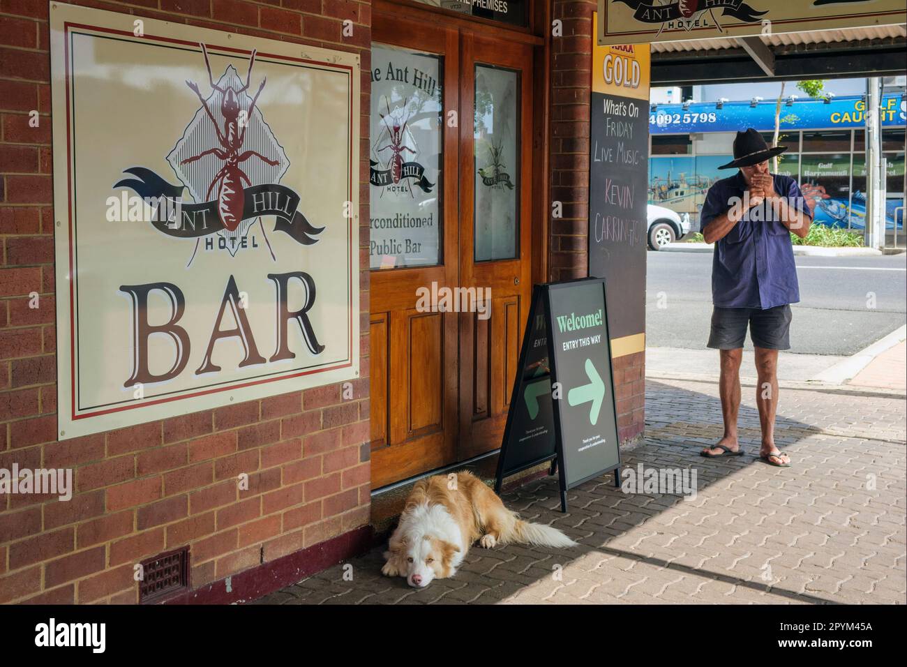A sleepy dog and a man lighting a cigarette on a street corner in Mareeba, Queensland, Australia Stock Photo