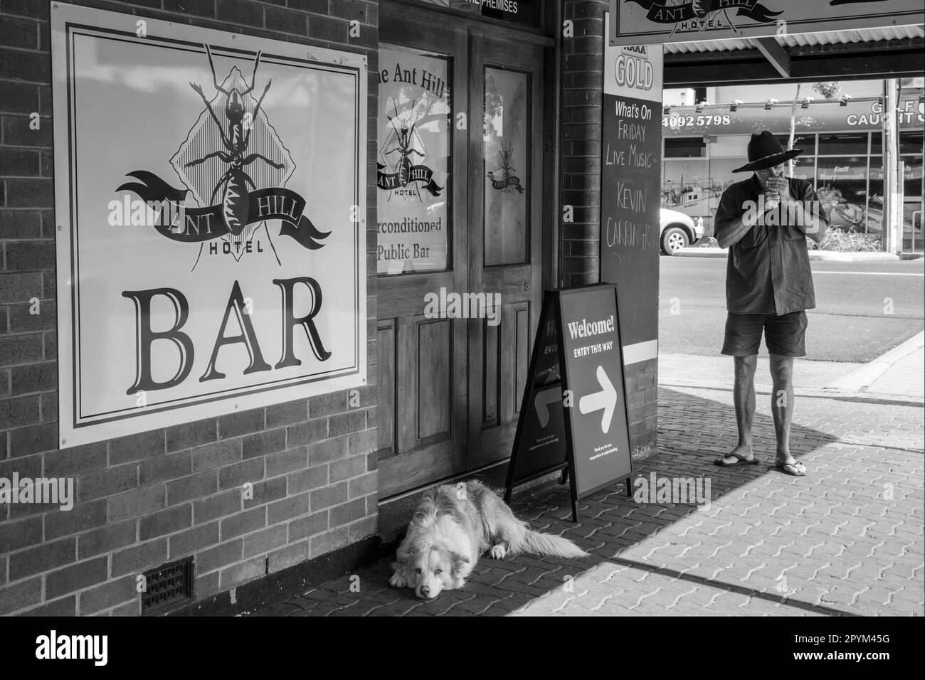 A sleepy dog and a man lighting a cigarette on a street corner in Mareeba, Queensland, Australia Stock Photo