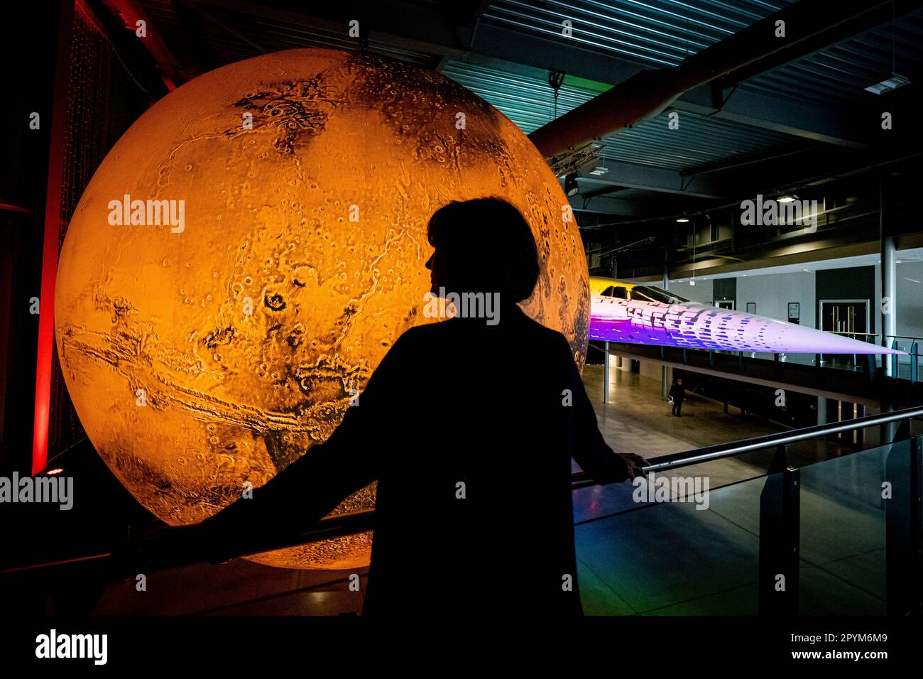 A person admires artist Luke Jerram's Mars installation at Aerospace Bristol, as part of a new Journey to Mars exhibition. The temporary exhibition marks the 20th anniversary of Mars Express, Europe's first mission to Mars, with models of the Mars Express Orbiter and the Beagle 2 lander on display alongside artist's Mars sculpture. Picture date: Thursday May 4, 2023. Stock Photo