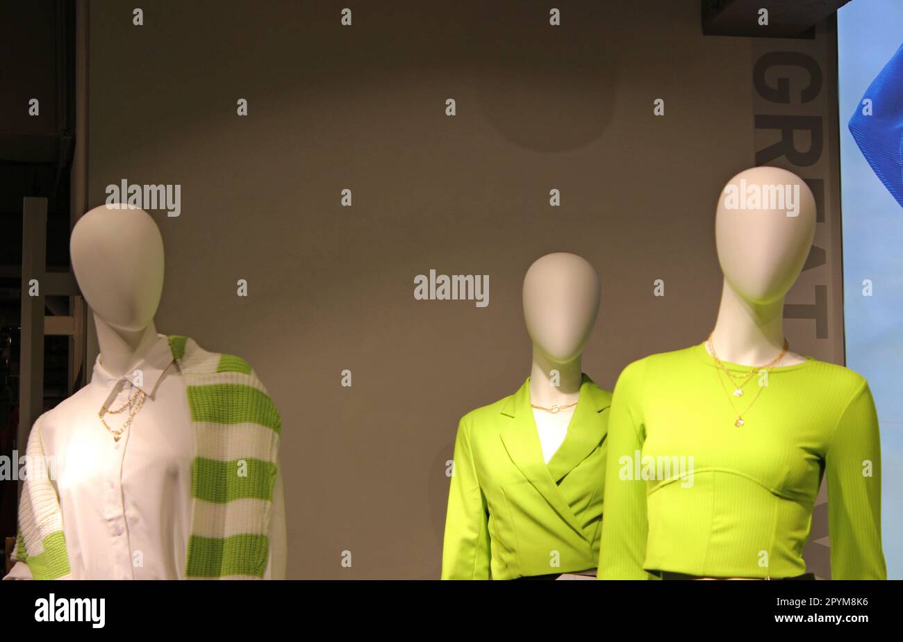 Three plastic mannequins without faces in the window of a women's clothing store Stock Photo
