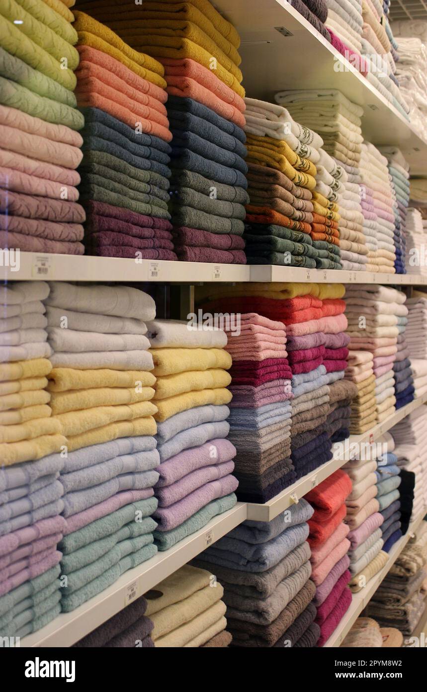 New colored terry towels folded stack on a shelf at fabric store Stock Photo