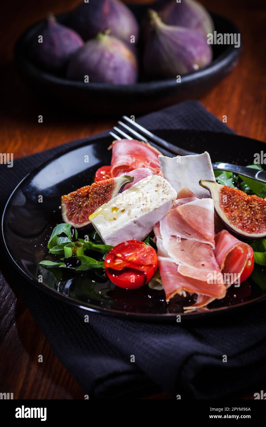 Antipasti plate with fresh figs, cheese and prosciutto Stock Photo