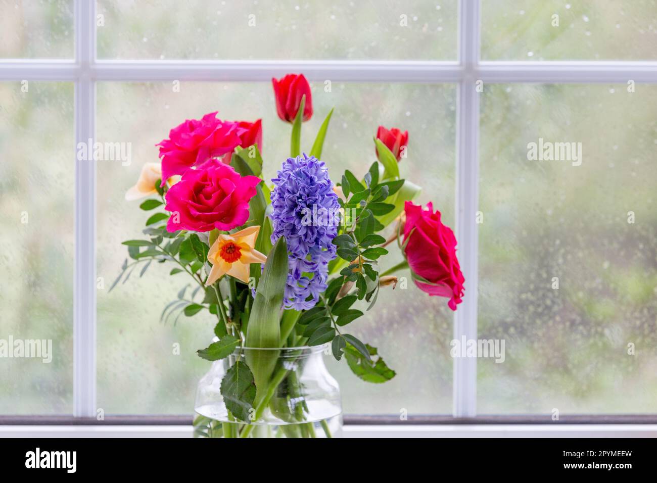 A vase of spring flowers (hyacinth, roses, daffodils and tulips) on a