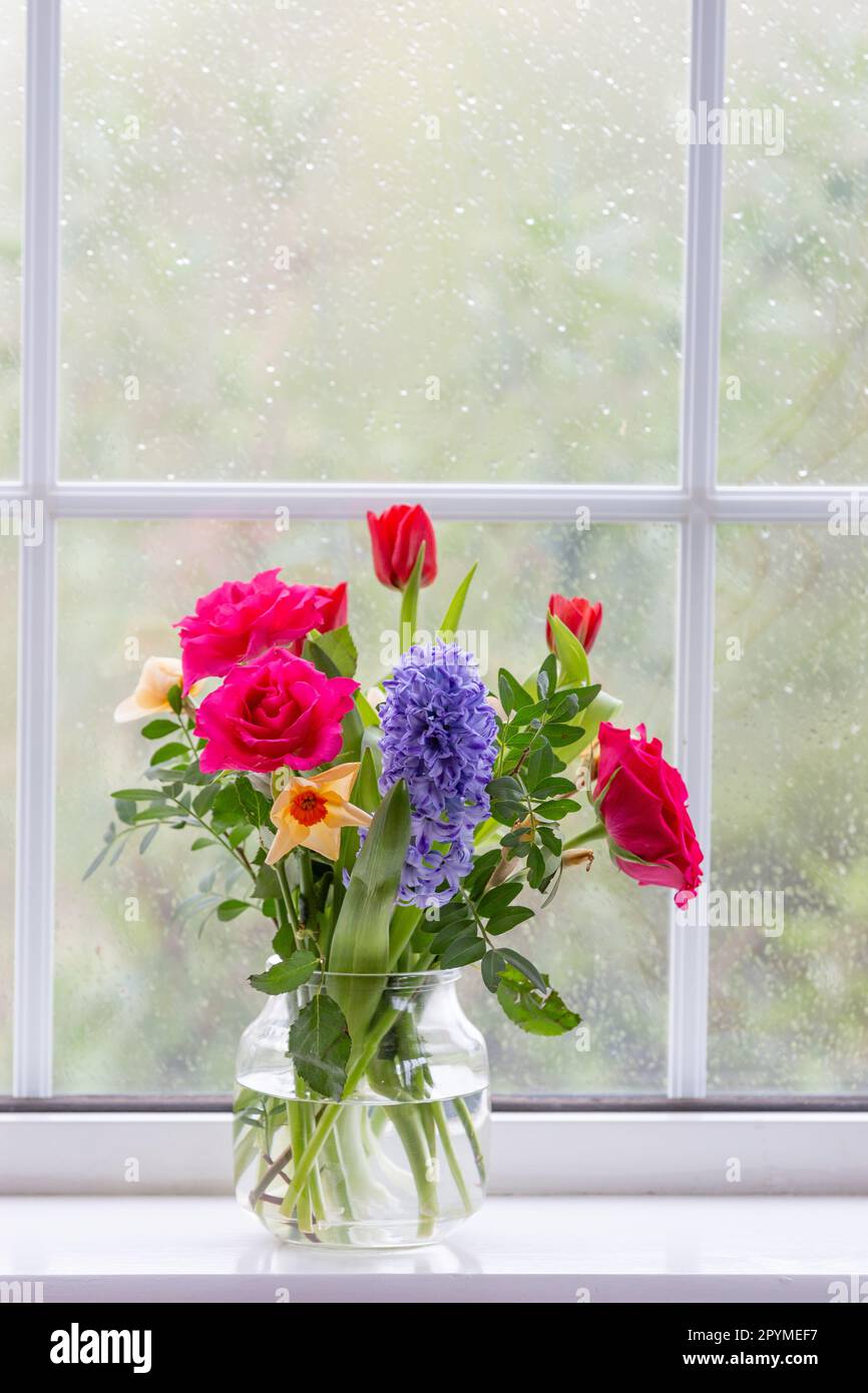 A vase of spring flowers (hyacinth, roses, daffodils and tulips) on a
