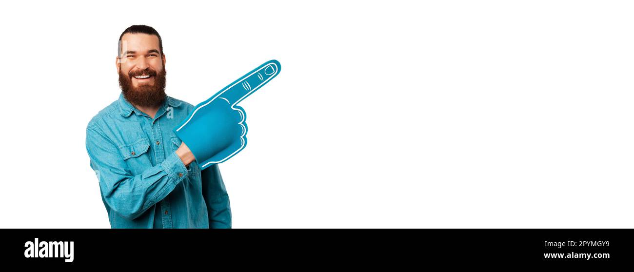Banner shot of a handsome man wearing blue shirt and foam finger foam pointing aside. Stock Photo