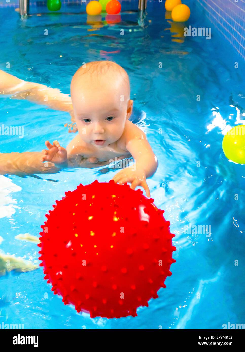 Adorable baby girl enjoying swimming in a pool with her mother early development class for