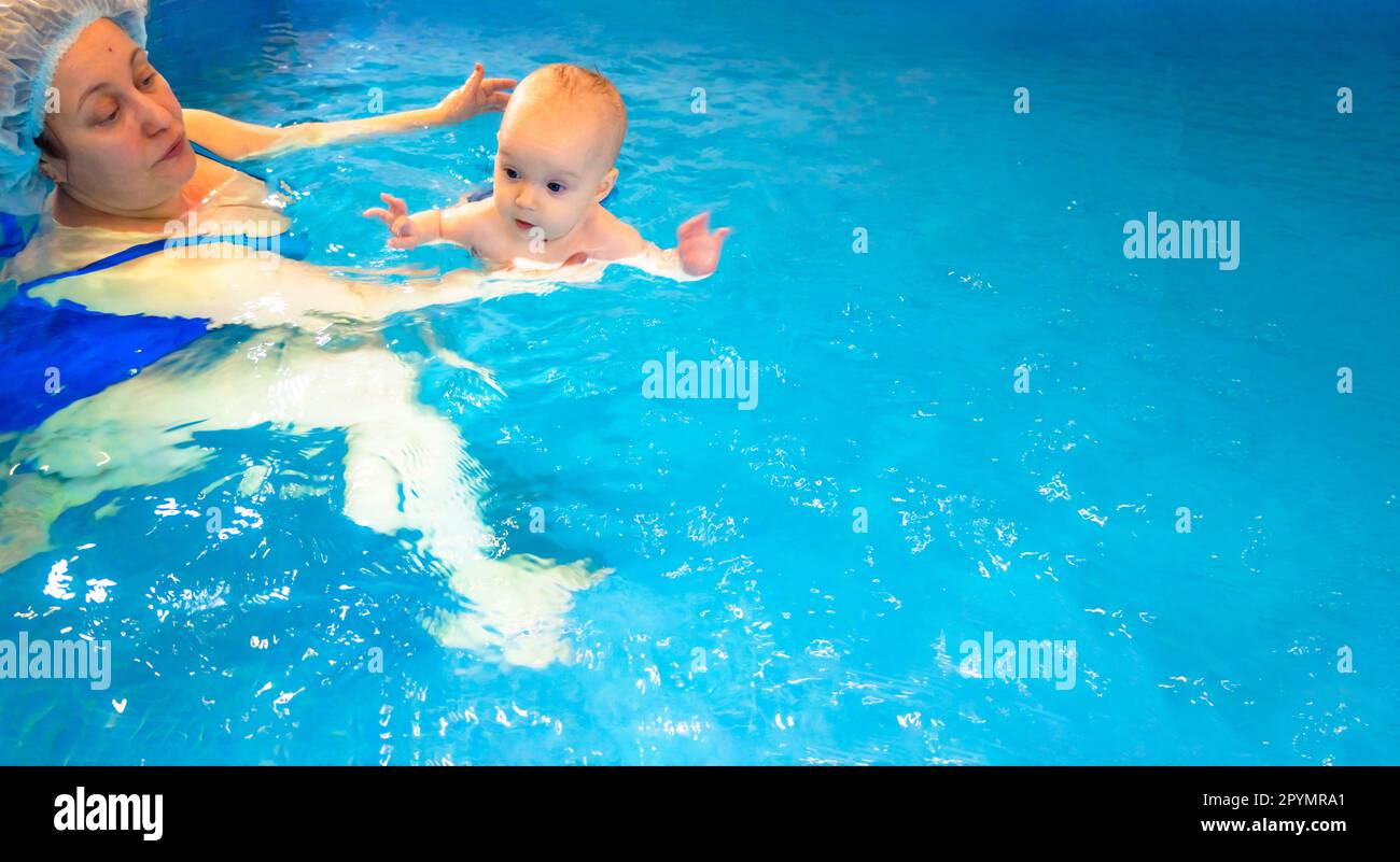 Adorable baby girl enjoying swimming in a pool with her mother early development class for